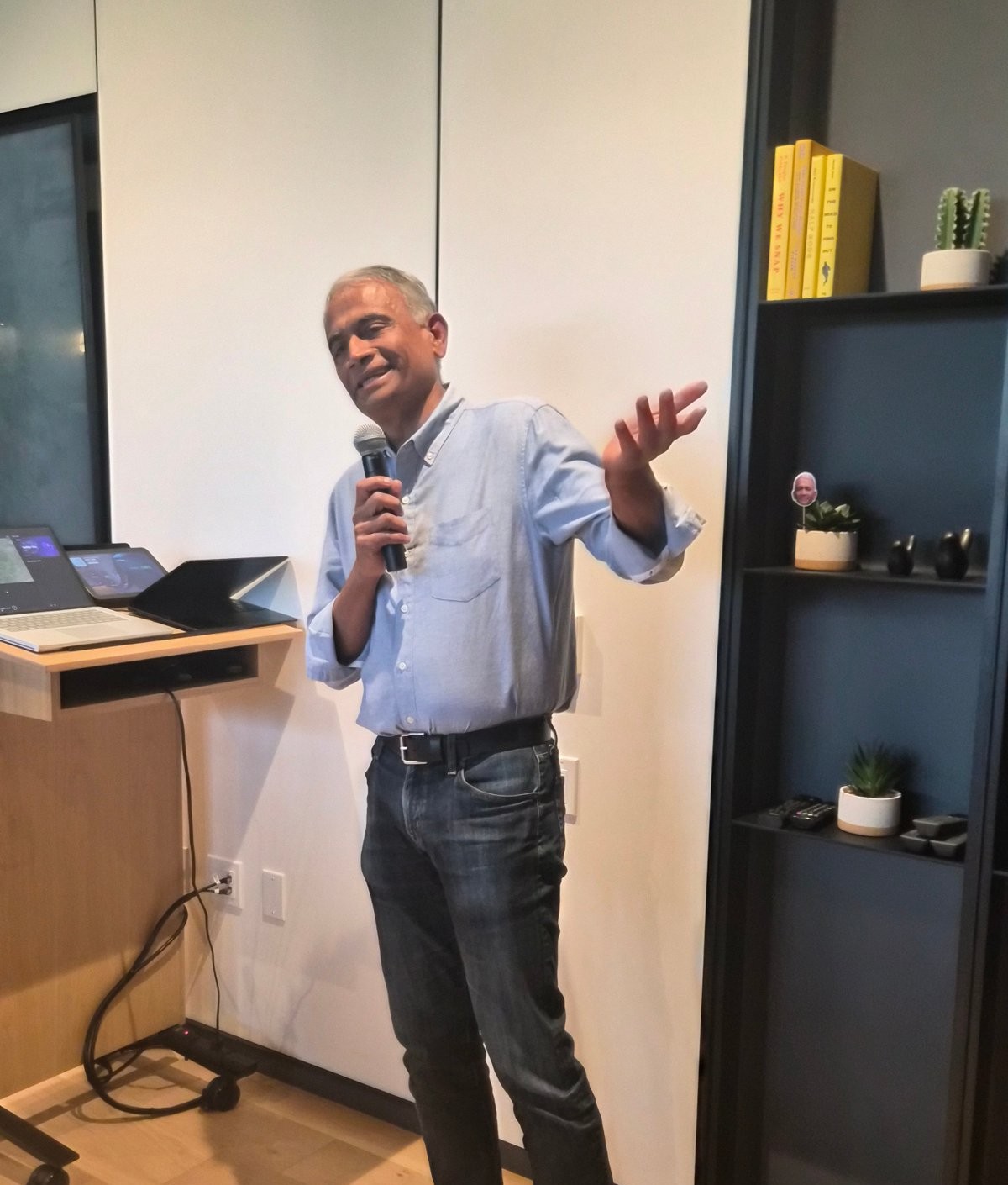 Rajesh speaking into a microphone at his retirement party