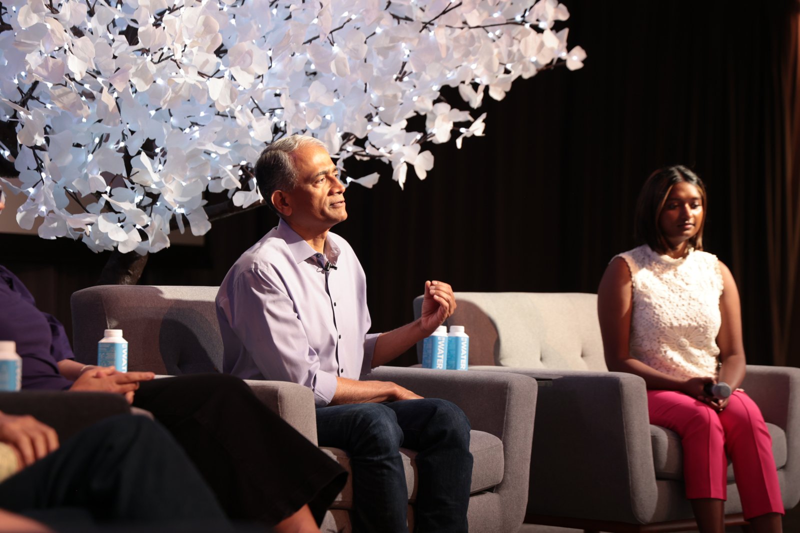 Rajesh speaking on a panel beneath a lit white tree